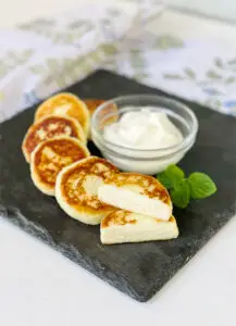 Gluten Free Cheese Pancakes on Display Showing The Inside Texture and Served with a Bowl of Sour Cream