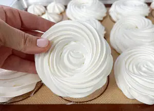 A hand holding the baked meringue nest