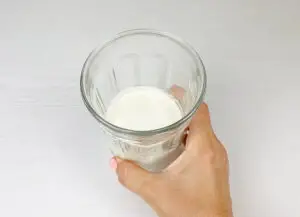 A hand holding a cup with heavy cream