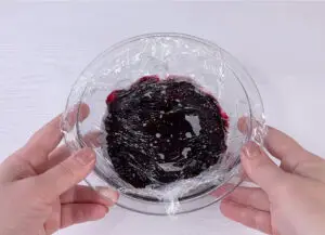 Berry sauce in the bowl covered with plastic wrap